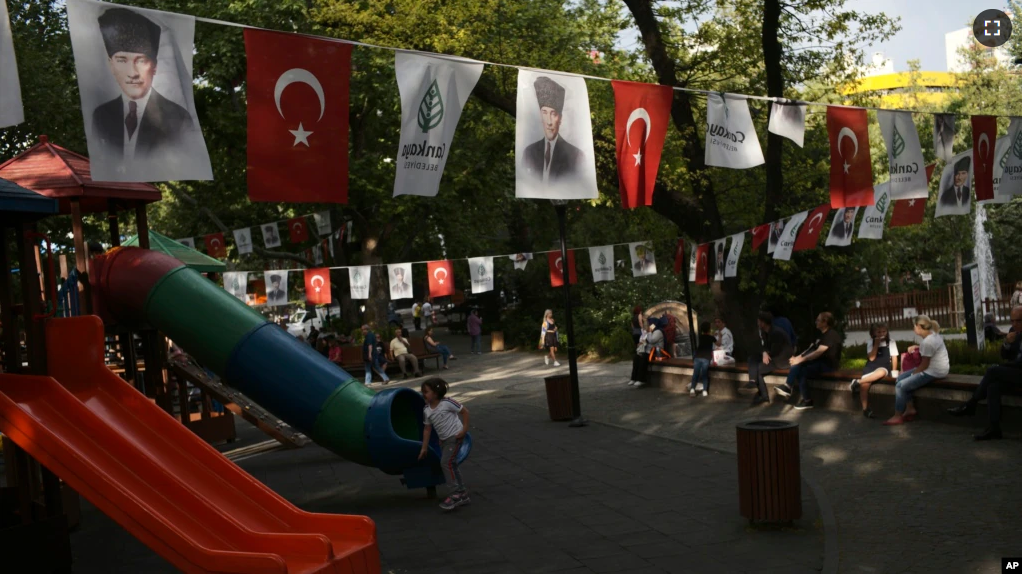 FILE - People sit at Kugulu public garden decorated with national flags and images of Turkey's founder Mustafa Kemal Ataturk, in Ankara, Turkey, Thursday, June 2, 2022. (AP Photo/Burhan Ozbilici)