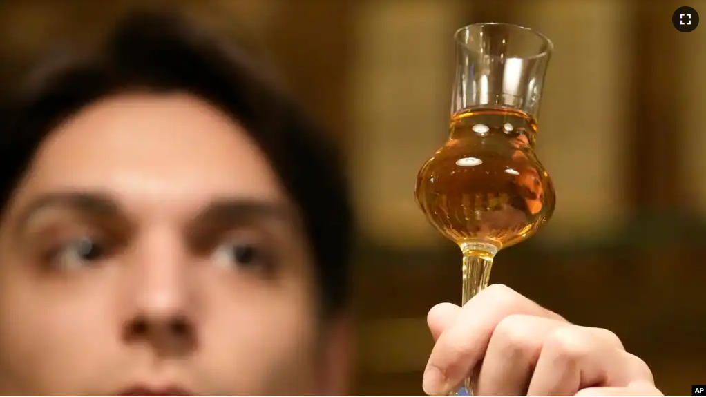 A barman looks at a glass with plum brandy in a bar in Belgrade, Serbia, Friday, Nov. 11, 2022. (AP Photo/Darko Vojinovic)