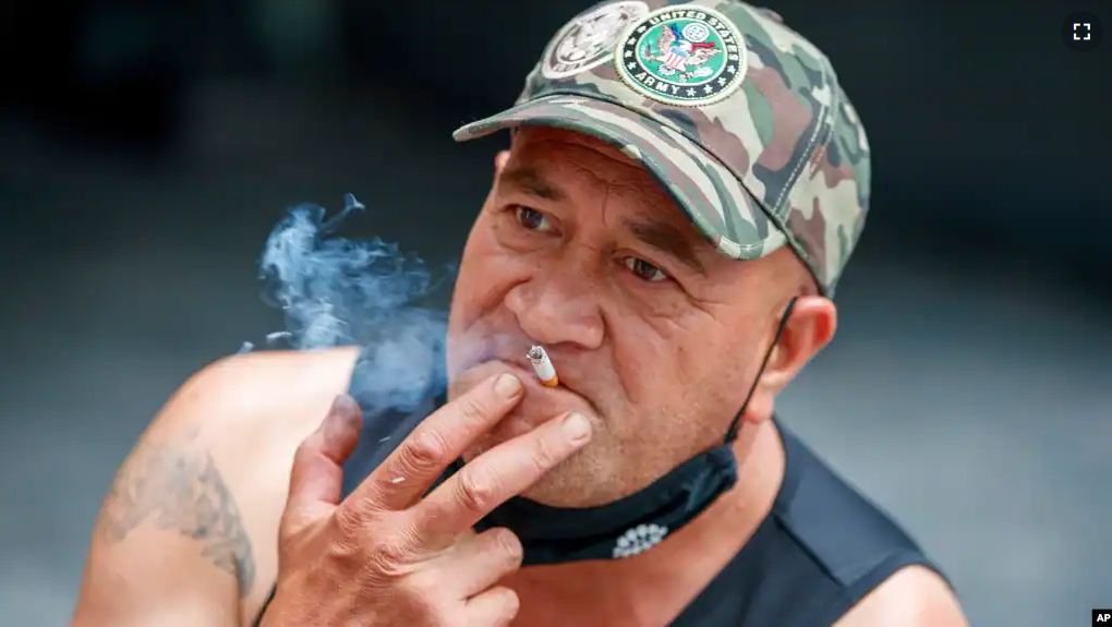 FILE - A man sits while smoking in Auckland, New Zealand, Thursday, Dec. 9, 2021. New Zealand on Tuesday passed into law a unique plan to phase out tobacco smoking by imposing a lifetime ban on young people buying cigarettes. (AP Photo/David Rowland, File)