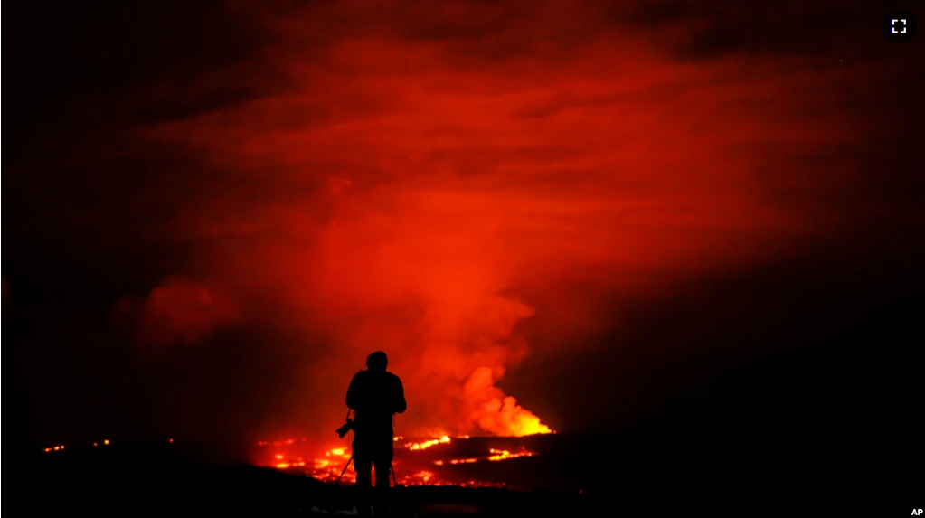 A photographer takes pictures of the Mauna Loa volcano as it erupts Wednesday, Nov. 30, 2022, near Hilo, Hawaii. (AP Photo/Gregory Bull)