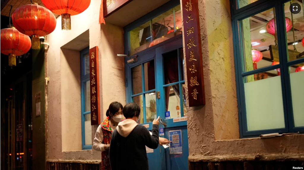 A waiter guides a customer to scan a health QR code outside a restaurant as coronavirus disease (COVID-19) outbreaks continue in Shanghai, China on December 8, 2022. (REUTERS/Aly Song)