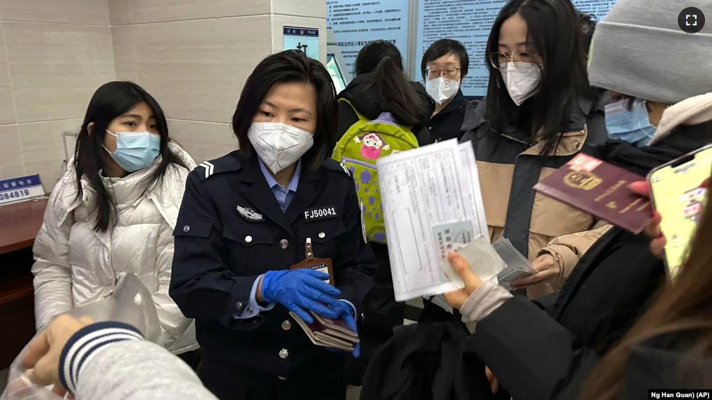 An officer collects passports from residents for renewal and re-applications at a community police station in Beijing, Wednesday, Dec. 28, 2022. (AP Photo/Ng Han Guan)