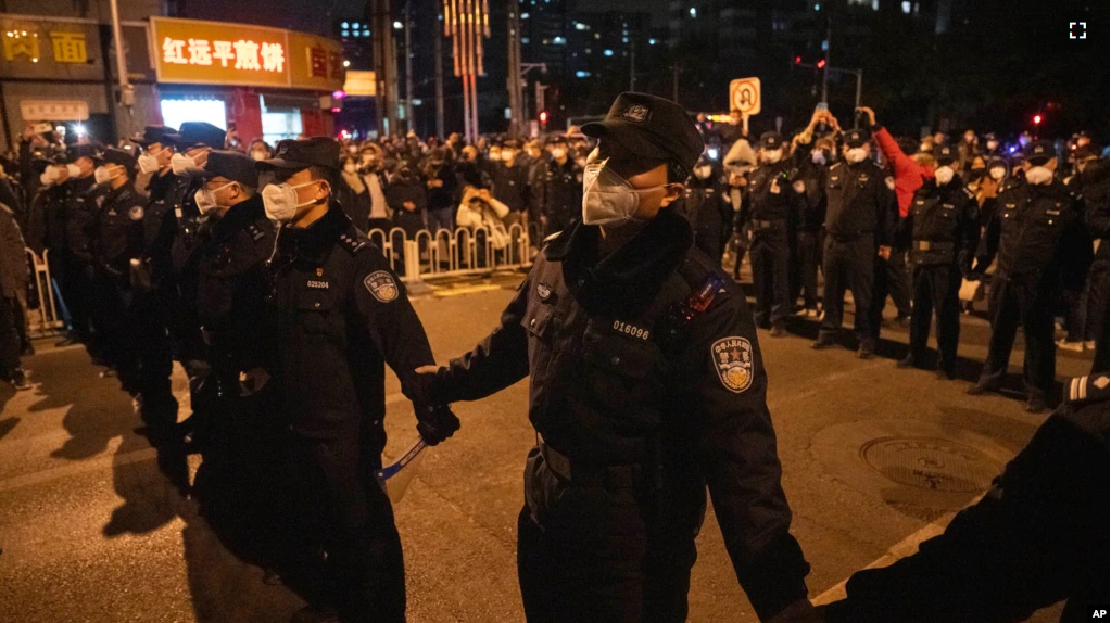 Chinese policemen form a line to stop protesters marching in Beijing, Sunday, Nov. 27, 2022. (AP Photo/Ng Han Guan)