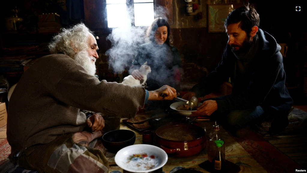 Fabrizio Cardinali, 72 and Cardinali's current housemates, Agnese, 35, and Andrea, 46, have lunch together at Cardinali's home in the woods of the small town of Cupramontana, Ancona, Marche, Italy, December 12, 2022. ( REUTERS/Yara Nardi )