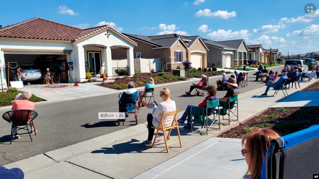 Neighbors of Lisa and Larry Neula watching them perform a Hawaiian dance in their driveway in Sacramento, Calif., in March 2022. The two began their driveway performances during lockdown and have kept them up. (John Pasamonte via AP)