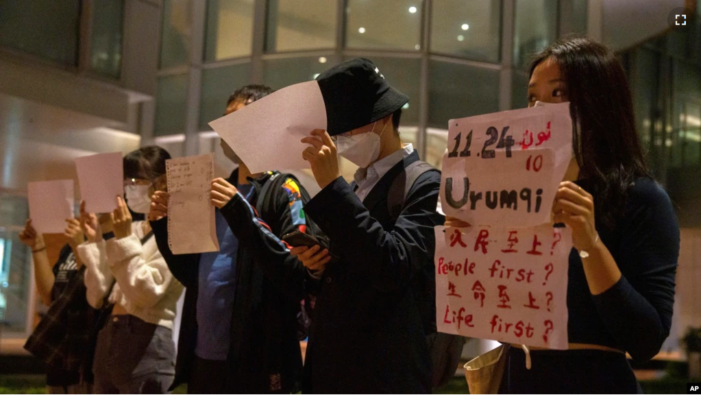 Protesters hold up white paper some with writings commemorating the Nov 24 deadly Urumqi fire during a gathering at the University of Hong Kong in Hong Kong, Tuesday, Nov. 29, 2022. (AP Photo/Bertha Wang)