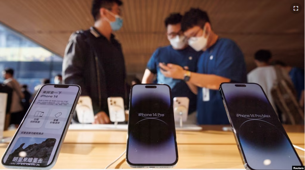 FILE - A customer talks to sales assistants in an Apple store as Apple new iPhone 14 models go on sale in Beijing, September 16, 2022. (REUTERS/Thomas Peter)