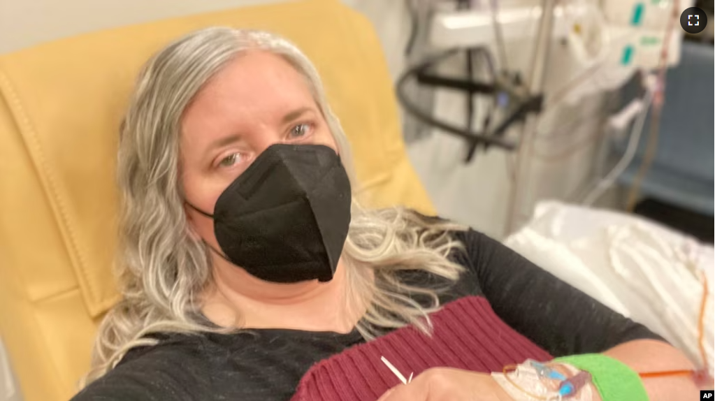 This photo provided by Amy Watson of Portland, Ore., shows her during an iron infusion in December 2022. Watson, approaching 50, says she has “never had any kind of recovery” from COVID-19.(Amy Watson via AP)