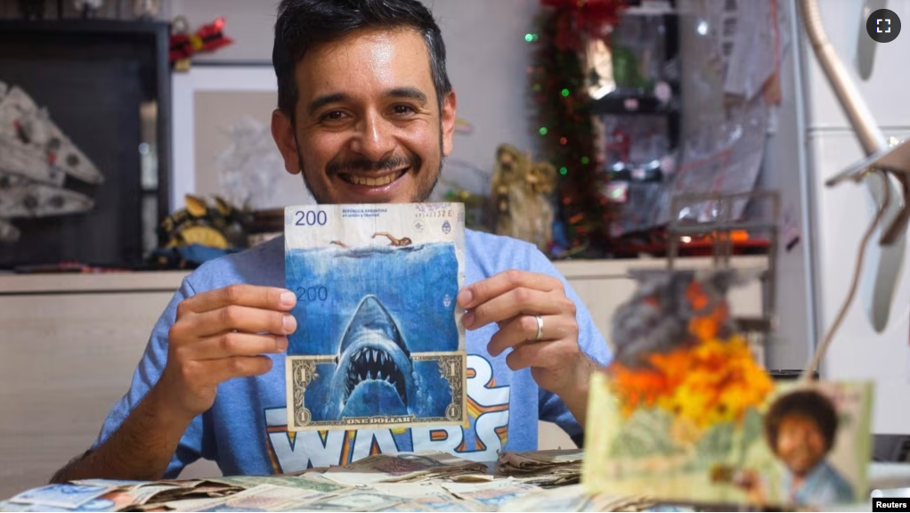 Artist Sergio Diaz holds intervened Argentine pesos bills and a US dollar depicting Steven Spielberg's movie "Shark" as a parody of Argentina's ever-increasing inflation, in Salta, Argentina, December 30, 2022. (REUTERS/Javier Corbalan)