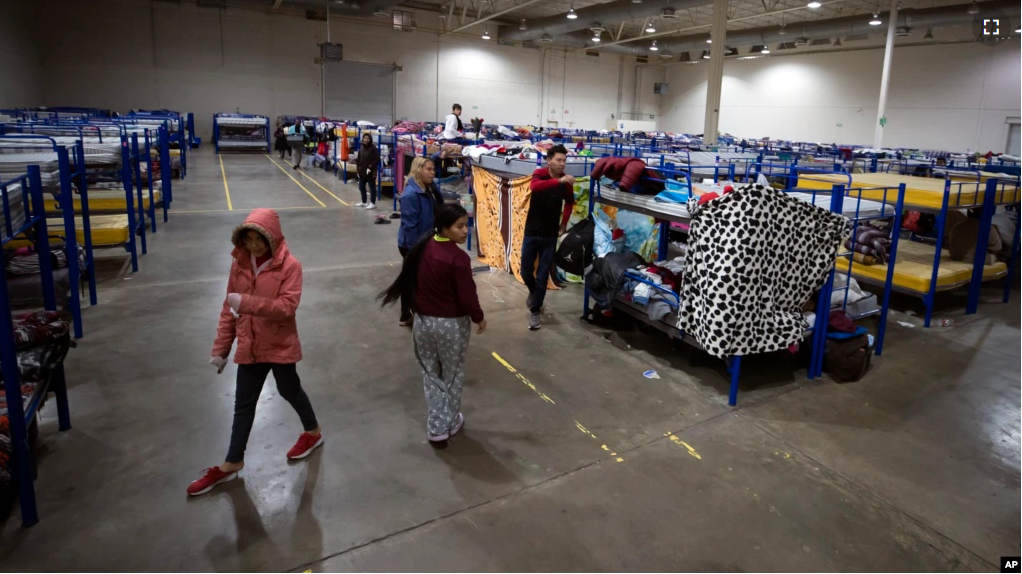 Migrants walk around bunk beds inside a government-run shelter in Ciudad Juarez, Mexico, on Sunday, Dec. 18, 2022. (AP Photo/Andres Leighton)