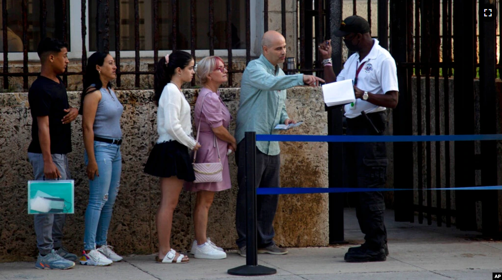 People stand in line outside the U.S. embassy on the day of its reopening for visa and consular services in Havana, Cuba, Jan. 4, 2023. (AP Photo/Ismael Francisco)