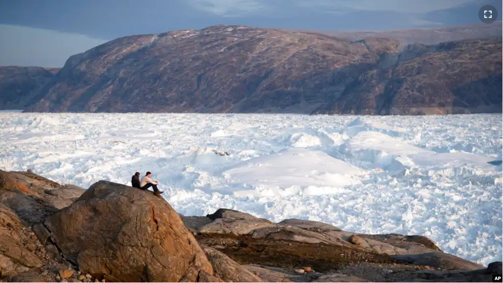 FILE - In this Aug. 16, 2019, photo, student researchers sit on top of a rock overlooking the Helheim glacier in Greenland.