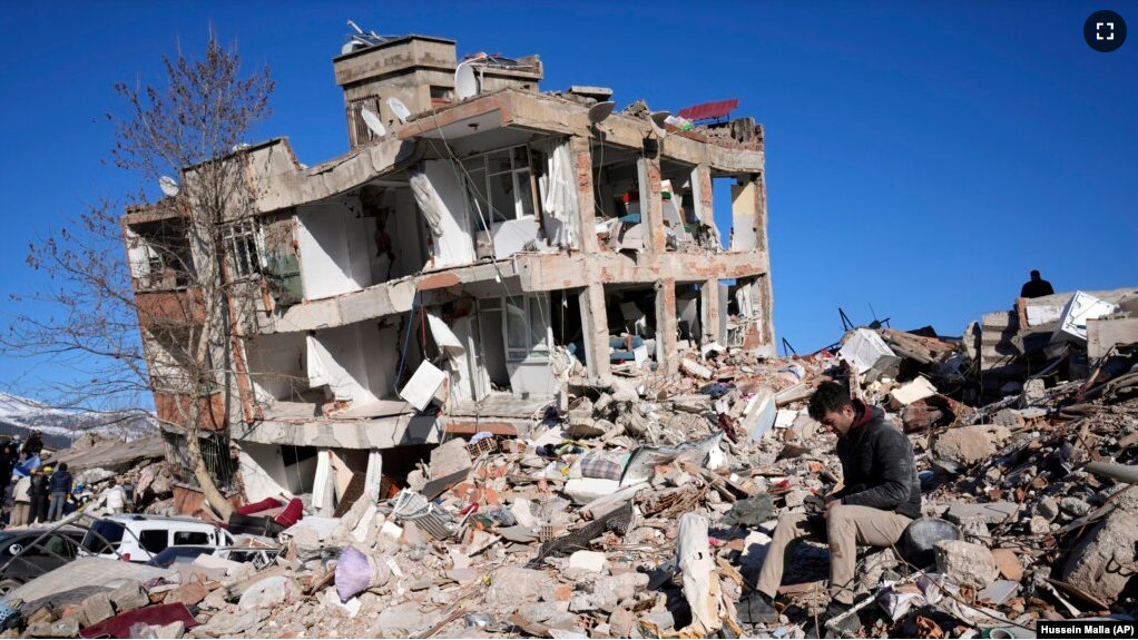 A man sits at his destroyed house in Kahramanmaras, southern Turkey, Wednesday, Feb. 8, 2023. (AP Photo/Hussein Malla)