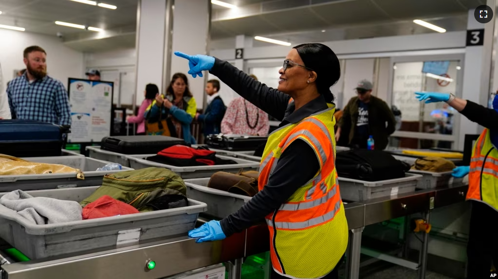 A worker points as people wait for the belongings at the Transportation Security Administration security area at the Hartsfield-Jackson Atlanta International Airport on Wednesday, Jan. 25, 2023, in Atlanta. (AP Photo/Brynn Anderson)