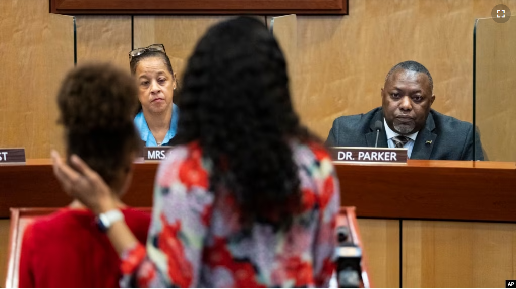 Djifa Lee, a second-grade teacher at Saunders Elementary, center, stands with her daughter as she speaks in front of the Newport News School Board at the Newport News Public Schools Administration building on Jan. 17, 2023. (Billy Schuerman/The Virginian-Pilot via AP, File)