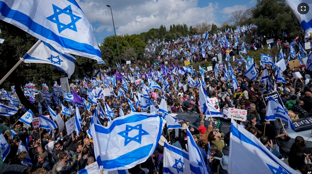 Israelis wave national flags during protest against plans by Prime Minister Benjamin Netanyahu's new government to overhaul the judicial system, outside the Knesset, Israel's parliament, in Jerusalem, Monday, Feb. 13, 2023. (AP Photo/Ohad Zwigenberg)