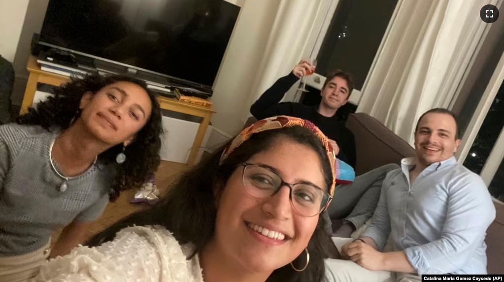 These close work friends, Catalina María Gomez Caycedo (foreground), Aleena Rupani, Henry Crabtree, and Michael Watkins meet in Crabtree's London apartment. (Photo provided by Catalina María Gomez Caycedo via AP)