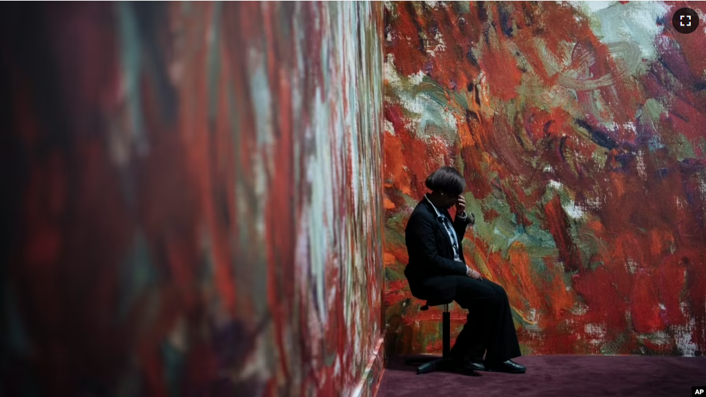 A guard sits by a painting in an exhibition on Leon Monet at the Musée du Luxembourg in Paris, Monday, March 13, 2023. (AP Photo/Lewis Joly)