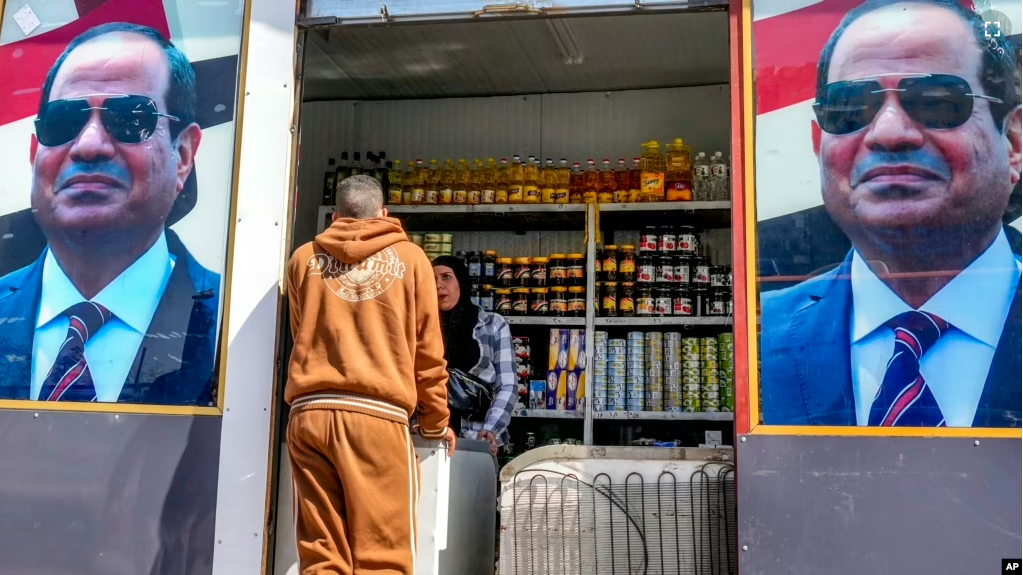 A man buys groceries at a government sponsored shop decorated with with Egyptian President Abdel Fattah el-Sissi posters in Cairo, Egypt, Sunday, Feb. 26, 2023. (AP Photo/Amr Nabil)