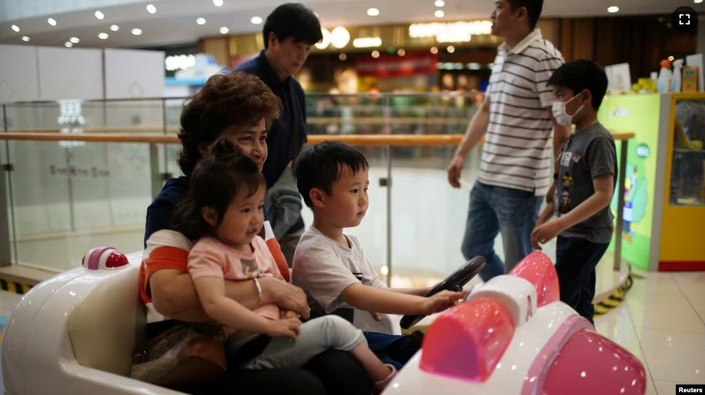 A person holds a girl as a boy drives a toy car at a shopping mall in Shanghai, China June 1, 2021. (REUTERS/Aly Song)