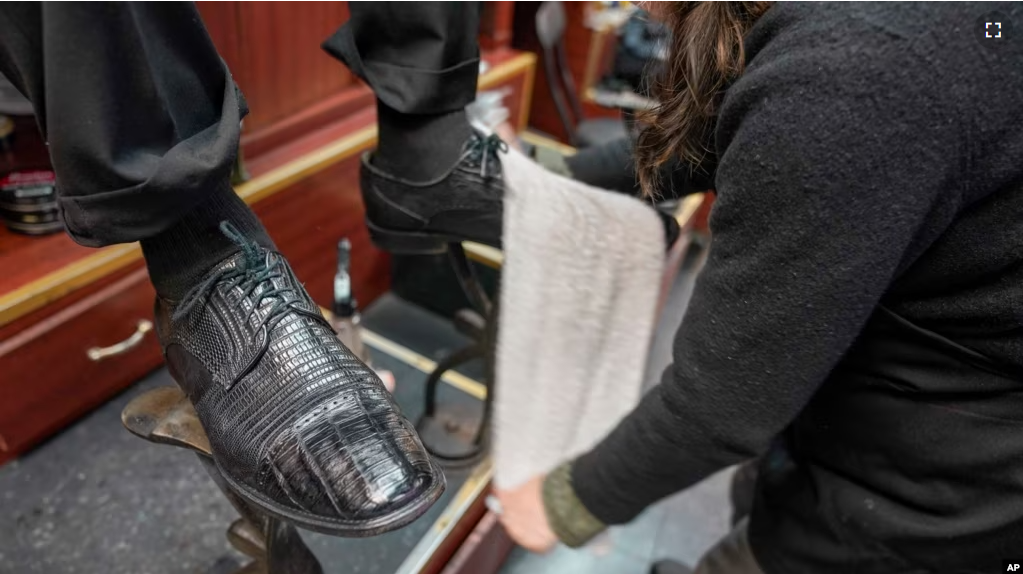 Bertha Gomez shines a customer's shoes at the Alpha Shoe Repair Corp., Friday, Feb. 3, 2023, in New York. Once a common business, the tradition of getting a quick shine like this one has become more of a rarity. (AP Photo/Mary Altaffer)