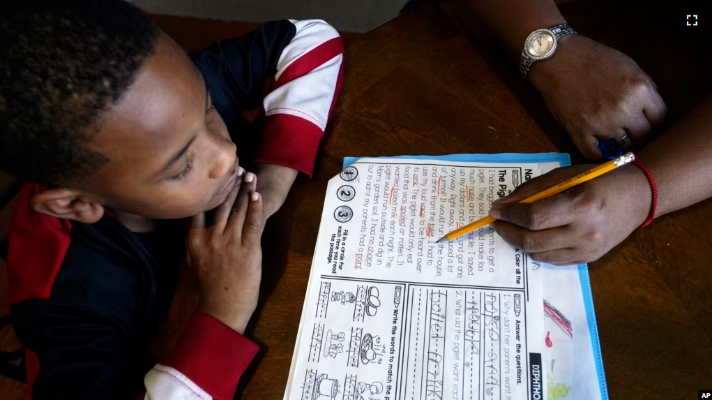 Christian Ensrud, 7, watches as his mother, Tamela Ensrud, help him with his homework at their home Monday, Nov. 21, 2022, in Nashville, Tenn. (AP Photo/Mark Humphrey)