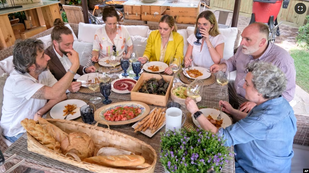 FILE - Diego Guerrero, from left, Carlos Sanchez, Mila, Ines Andres, Carlota Andres, Jose Andres and Pepa Muñoz enjoy a meal in a scene from the Discovery + television series "Jose Andres and Family in Spain." (Xaume Olleros/Discovery via AP)