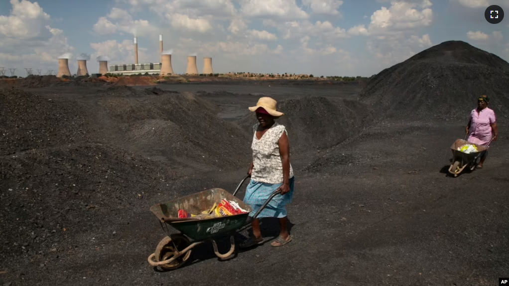 FILE - Women push wheelbarrows atop a coal mine dump at the coal-powered Duvha power station, near Emalahleni east of Johannesburg, Nov. 17, 2022. (AP Photo/Denis Farrell, File)