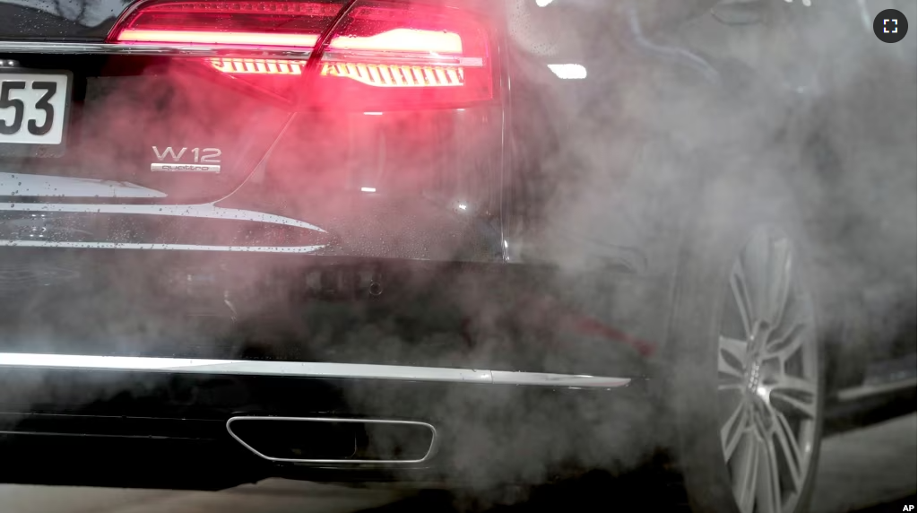 In this file photo, a luxury Audi car is surrounded by exhaust gases as it is parked with a running engine in front of the Chancellery in Berlin, Germany, Wednesday, Nov. 20, 2019. (AP Photo/Michael Sohn, File)