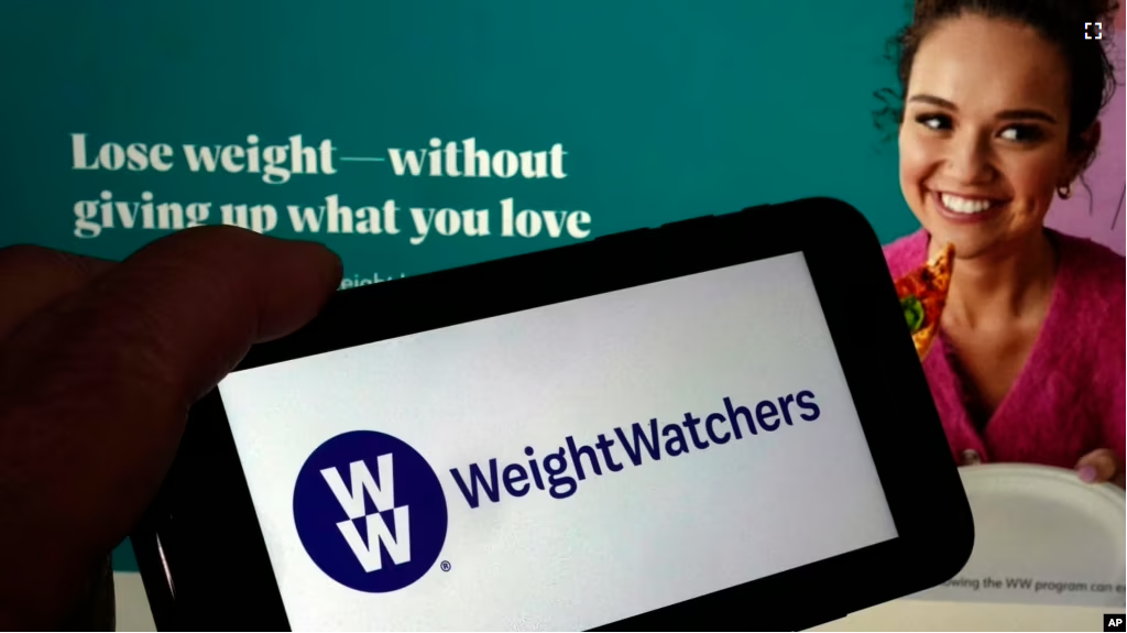 This image shows the logo of WeightWatchers on a mobile phone, and the company's website on March 7, 2023. (AP Photo/Richard Drew)