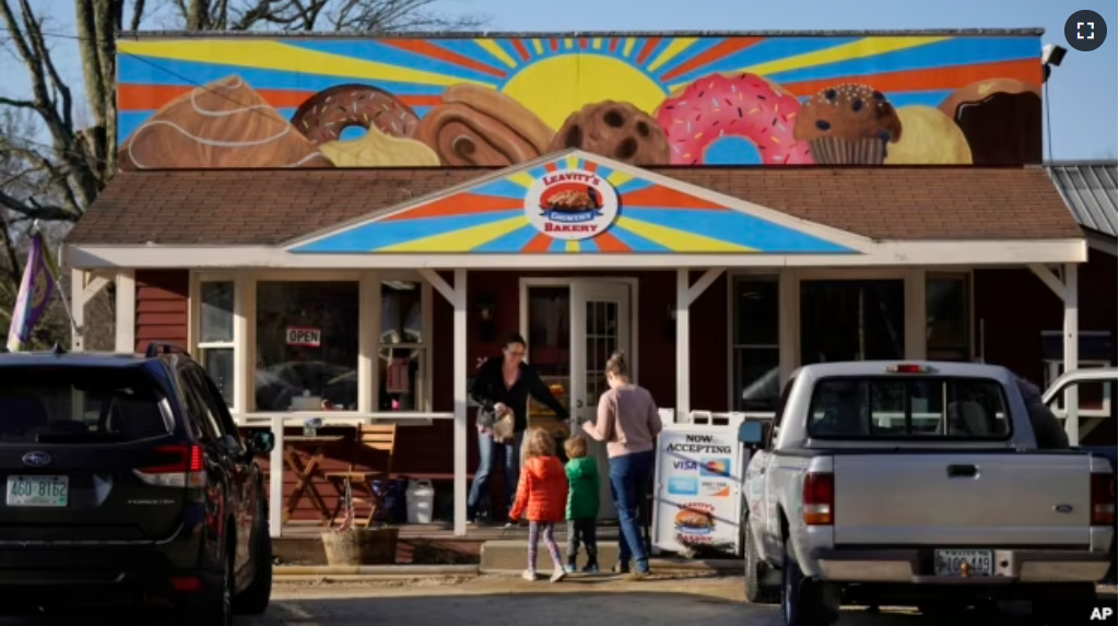 A customer holds the door for a family arriving at Leavitt's Country Bakery, Thursday, April 13, 2023, in Conway, N.H. (AP Photo/Robert F. Bukaty)