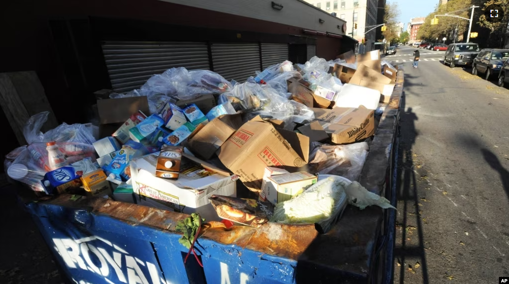 FILE - A dumpster filled with spoiled food waits for removal behind a Key Food supermarket in the still powerless East Village section of Manhattan, November 01, 2012, in New York.