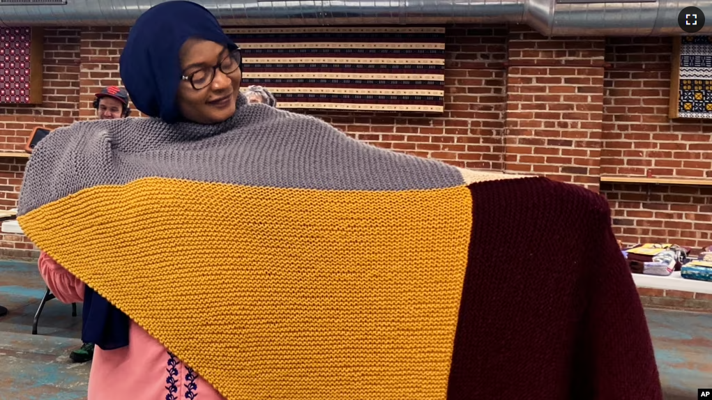 Aisha Bitini holds a handmade blanket she selected at a Welcome Blanket giveaway at the Association of Africans Living in Vermont on March 21, 2023, in Burlington, Vt. The blankets were to welcome refugees to the community. (AP Photo/Lisa Rathke)