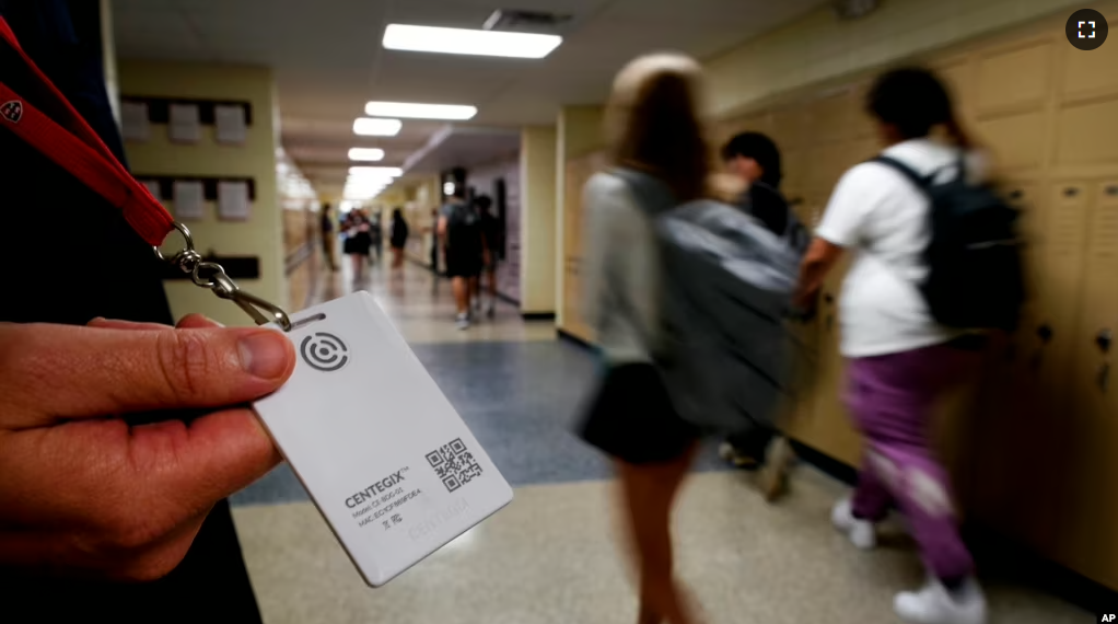 FILE - Brent Kiger, Olathe Public Schools' director of safety service, displays a panic-alert button while students at Olathe South High School rush between classes, Aug. 19, 2022, in Olathe, Kansas. (AP Photo/Charlie Riedel, File)