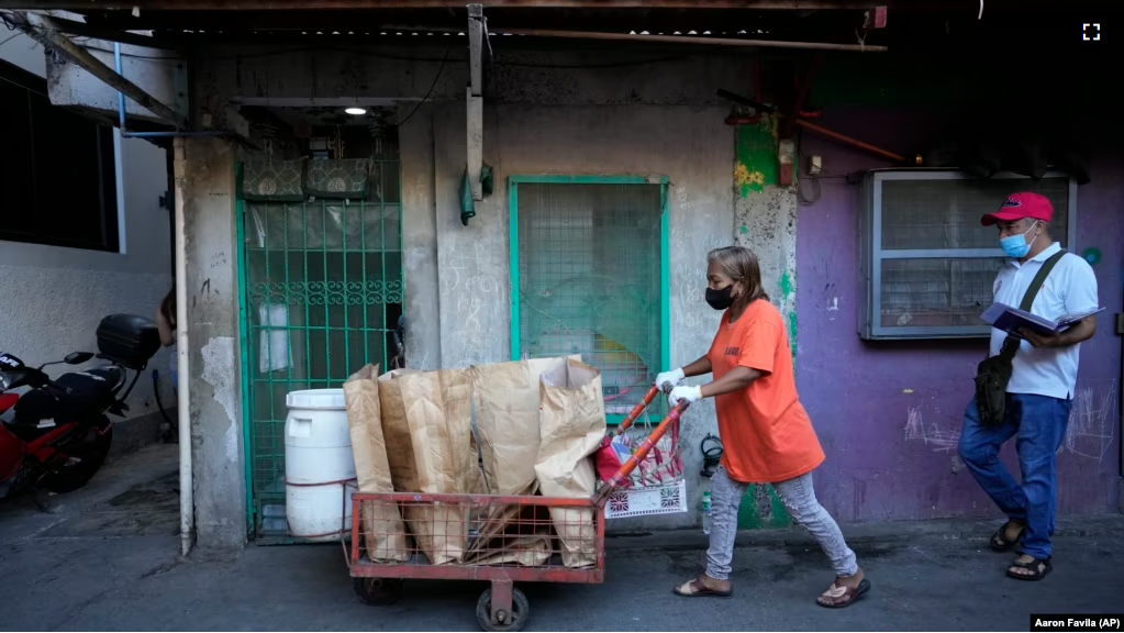 Marilene Capentes pushes her cart of separated garbage along the streets of Malabon, Philippines on Feb. 13, 2023. (AP Photo/Aaron Favila)