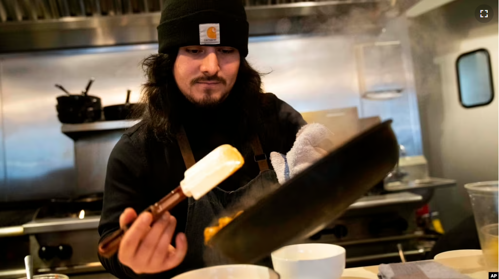 Santos Enrique Camara, 27, who dropped out of Shoreline Community College at age 19 in 2015, prepares food at Capers + Olives Friday, March 24, 2023, in Everett, Wash. (AP Photo/Lindsey Wasson)