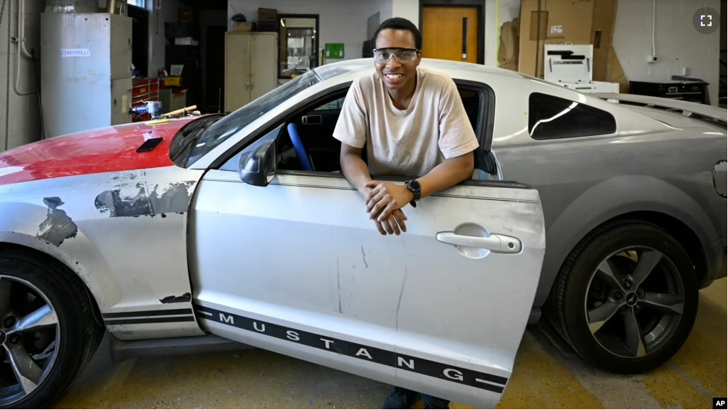 Tennessee College of Applied Technology Nashville student Robert Nivyayo poses with his car during auto collision repair class Wednesday, April 13, 2023. (AP Photo/John Amis)