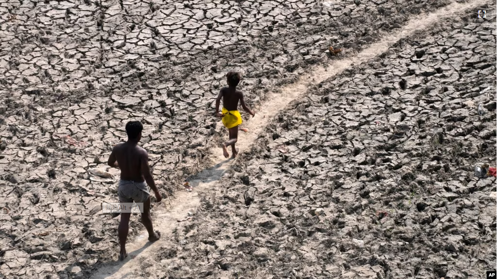 FILE - A man and a boy walk across a dried-up bed of river Yamuna in New Delhi, India, May 2, 2022. (AP Photo/Manish Swarup, File)