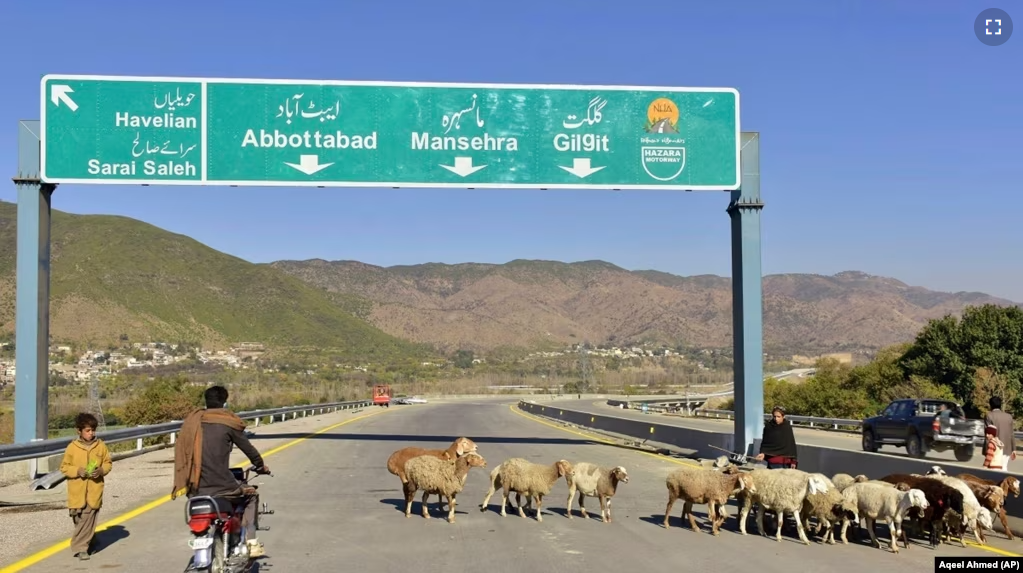 FILE - A motorcyclist drives past sheep on a newly built road in Haripur, Pakistan, on Dec. 22, 2017. China launched the Belt and Road Initiative in 2013 to expand its trade and influence by building roads, ports and other infrastructure overseas. (AP Photo/Aqeel Ahmed, File)