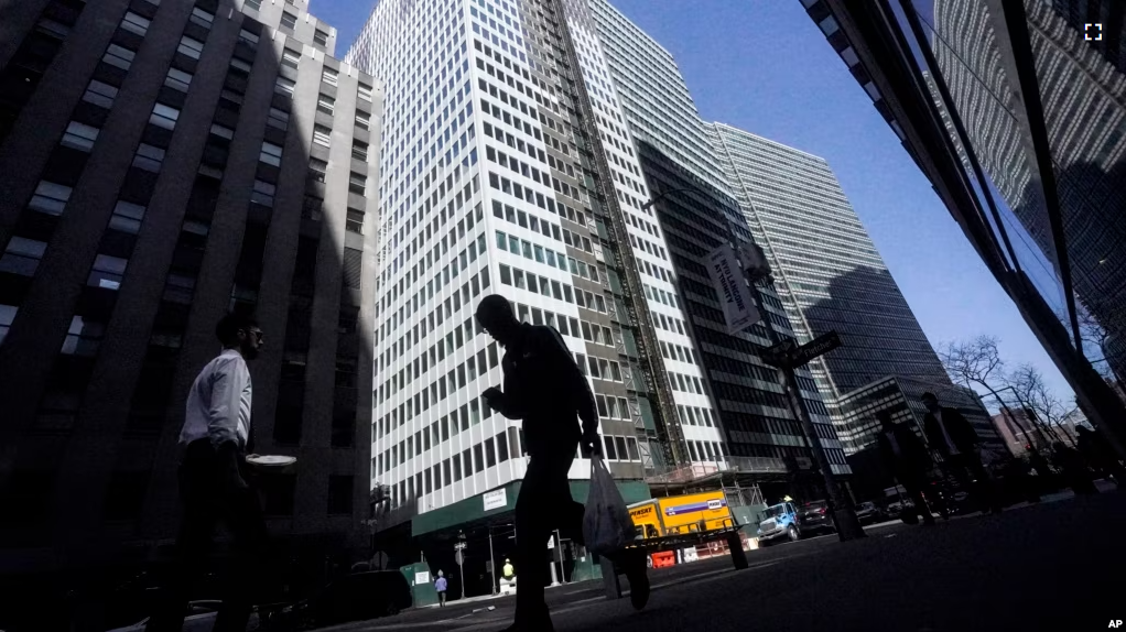 FILE - A pedestrian is silhouetted against a high rise at 160 Water Street in Manhattan's financial district, as the building is undergoing a conversion to residential apartments, Tuesday, April 11, 2023, in New York. (AP Photo/Bebeto Matthews)