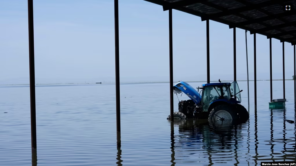 A tractor sits in flood water on the Hansen Ranches property after a series of storms Tuesday, April 25, 2023, in Corcoran, Calif. (AP Photo/Marcio Jose Sanchez)