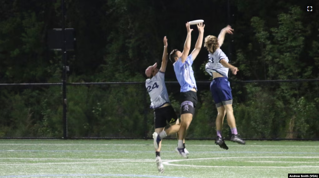 Jayden Feagans of the University of North Carolina's Darkside ultimate frisbee team makes a catch between two members of the Carolina Flyers in Chapel Hill, North Carolina, Thursday April 13, 2023 (VOA Photo/Andrew Smith)