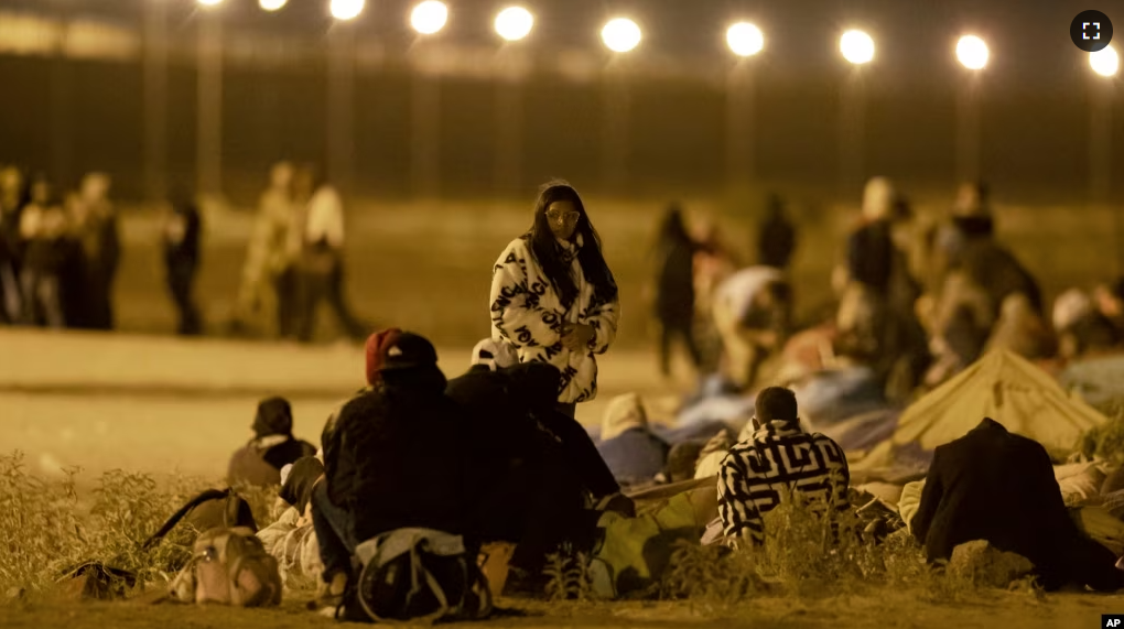 Migrants wait in the cold at a gate in the border fence after crossing from Ciudad Juarez, Mexico, into El Paso, Texas, in the early hours of May 11, 2023. (AP Photo/Andres Leighton)