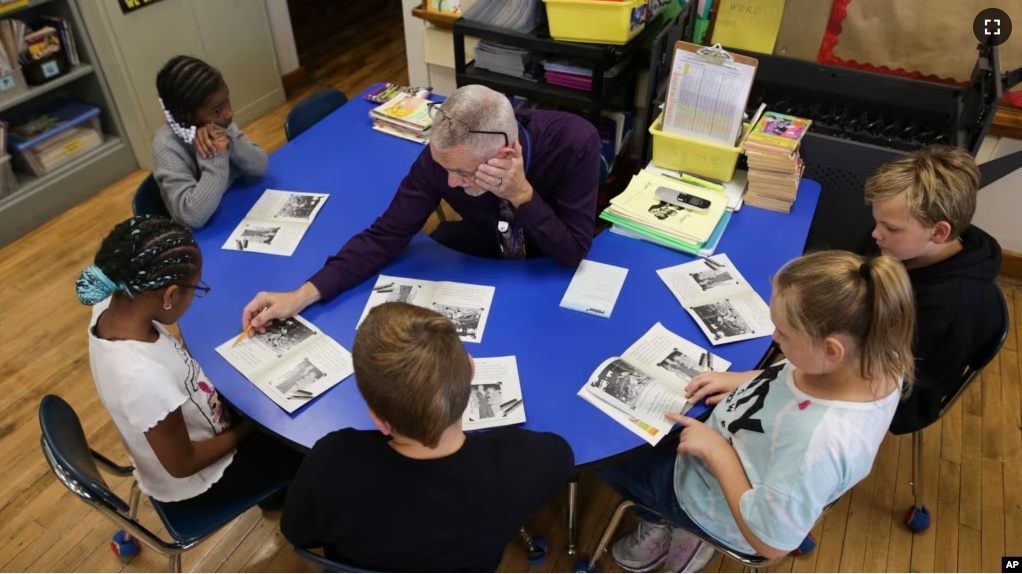 Richard Evans, a teacher at Hyde Park Elementary School, helps Ke'Arrah Jessie sound out a word during a reading circle in class on Thursday, Oct. 20, 2022, in Niagara Falls, N.Y. (AP Photo/Joshua Bessex)