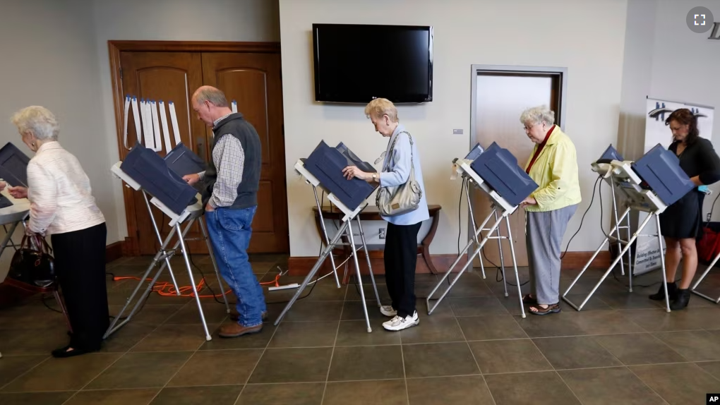 FILE - Voters fill the electronic voting machines to cast their ballots during the primary election at the precinct in the Highland Colony Baptist Church in Madison, Miss., on Tuesday, March 8, 2016. (AP Photo/Rogelio V. Solis)