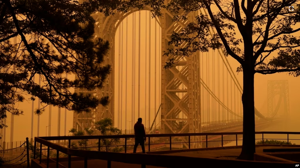 FILE - A man talks on his phone as he looks through the haze at the George Washington Bridge in Fort Lee, N.J., June 7, 2023. Thick, smoky air from Canadian wildfires made for days of misery in New York City and across the U.S. Northeast recently. (AP Photo/Seth Wenig, File)