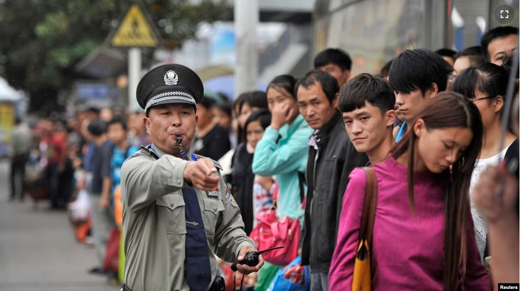 FILE - A security guard blows a whistle at a bus stop outside a railway station Hefei, Anhui province during a busy time, Oct. 7, 2013. (Reuters photo)