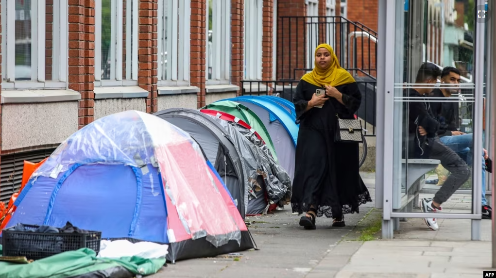 A woman walks past tents at a makeshift refugee camp outside the Irish Governments International Protection Office, in Dublin, Ireland, on June 12, 2023. (Photo by PAUL FAITH / AFP)