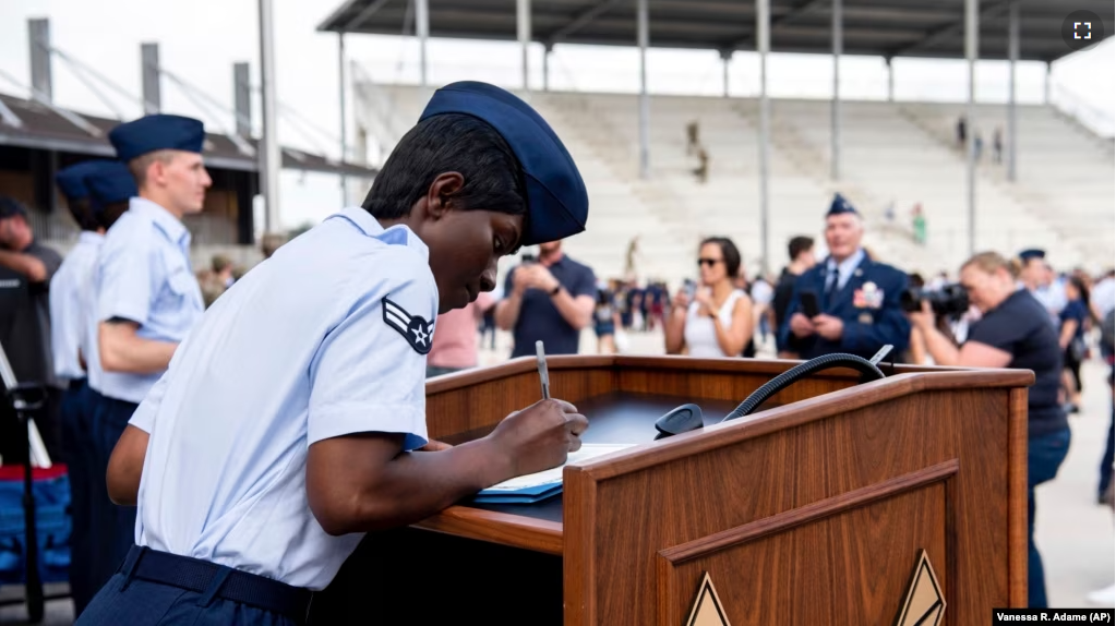 Airman 1st Class D'elbrah Assamoi, from Cote D'Ivoire, signs her U.S. certificate of citizenship after the Basic Military Training Coin Ceremony at Joint Base San Antonio-Lackland, in San Antonio, April 26, 2023. (Vanessa R. Adame/U.S. Air Force via AP)