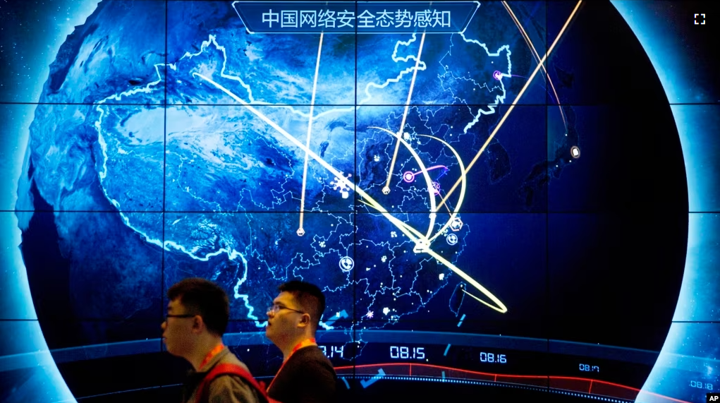 FILE - Attendees walk past a display showing cyberattacks in China at the China Internet Security Conference in Beijing, on Sept. 12, 2017. (AP Photo/Mark Schiefelbein, File)